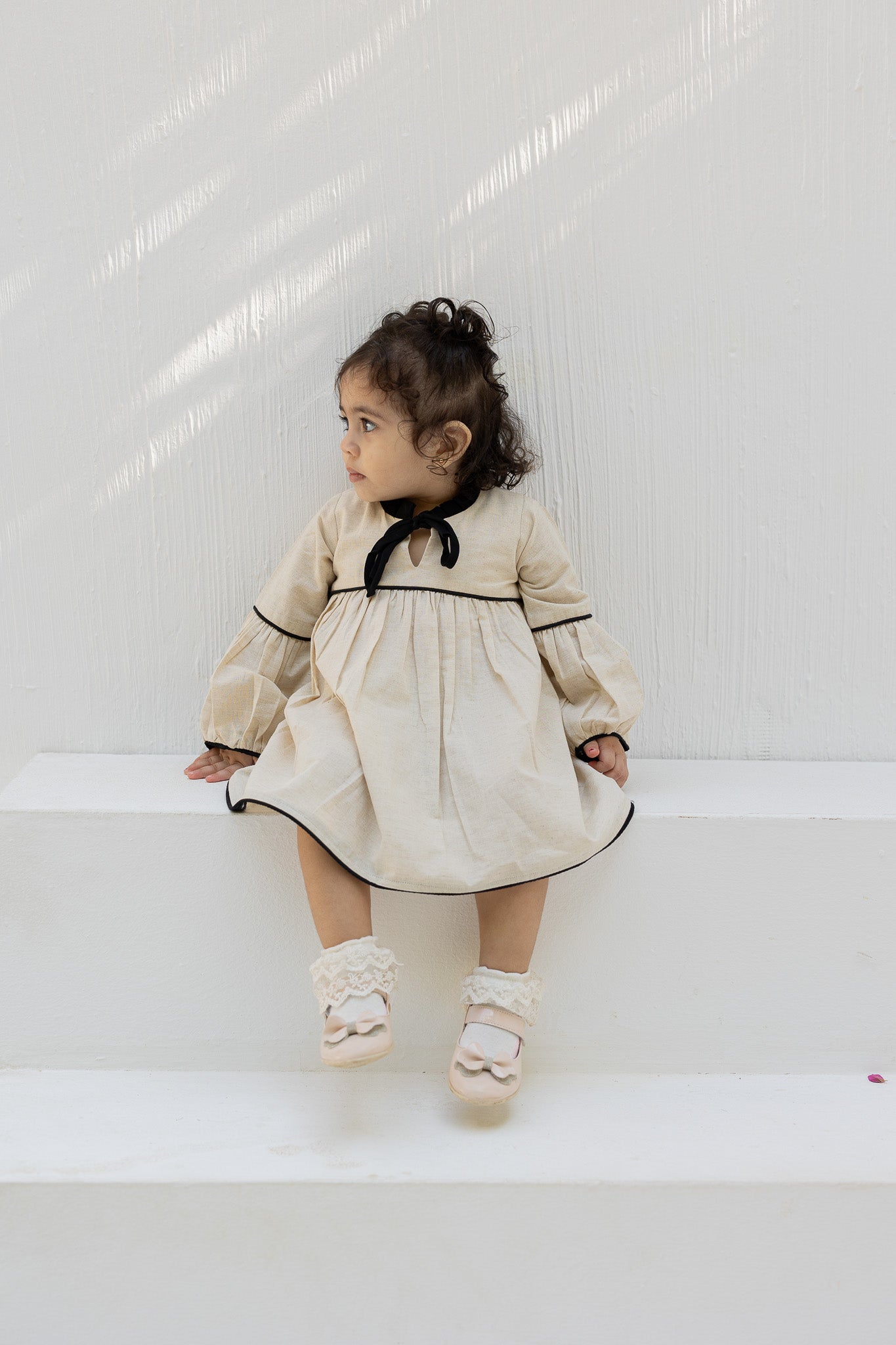 Eclipse Cream Baby Dress with Black Trim and Bow Detail